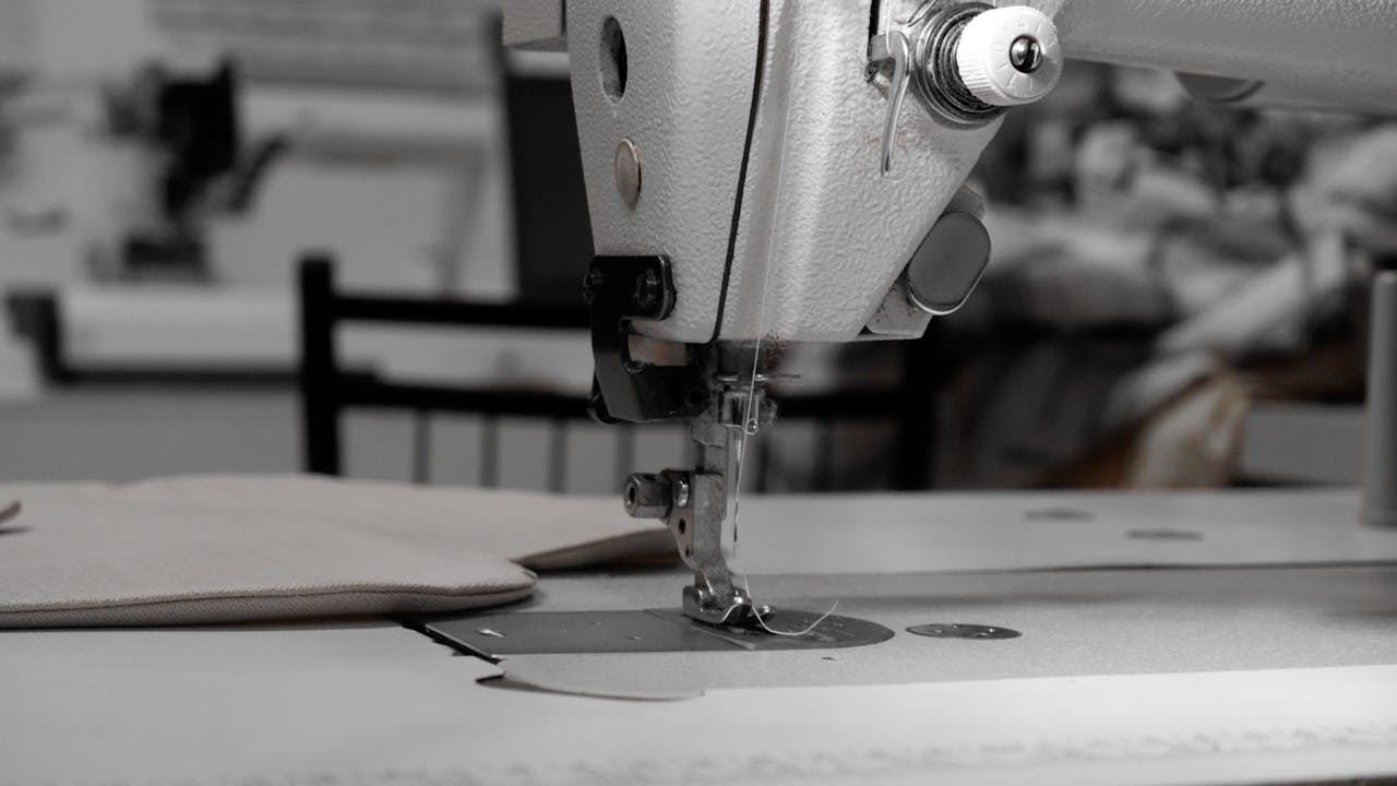 journey Closeup of an industrial sewing machine in a textile factory, focused on needle and fabric.