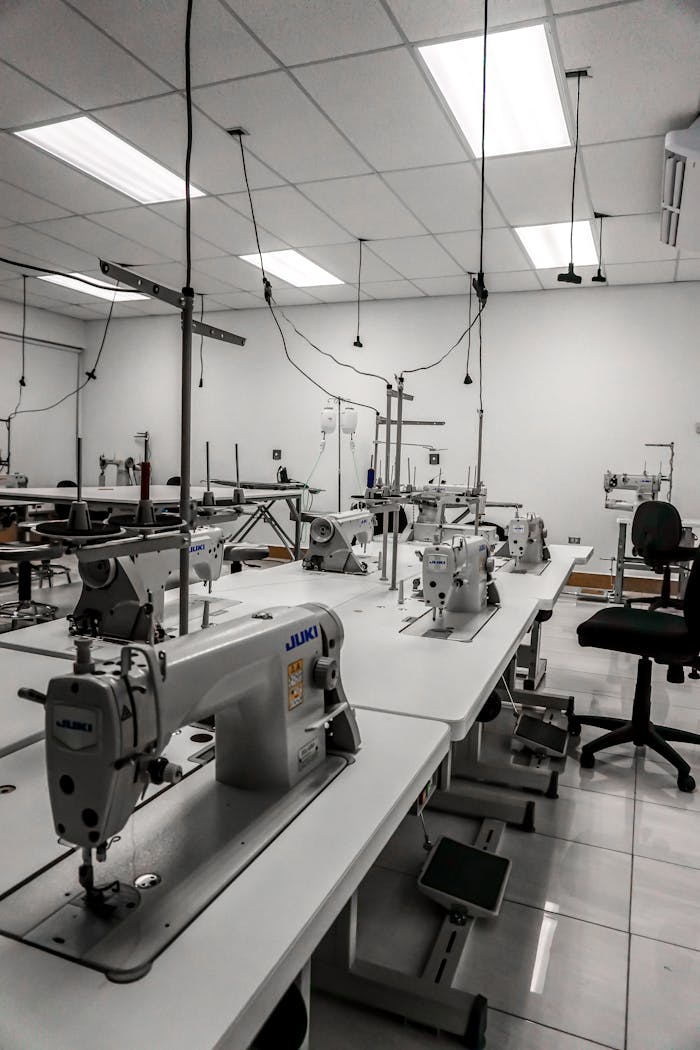 Industrial sewing machines in a well-lit factory room, ready for textile production.